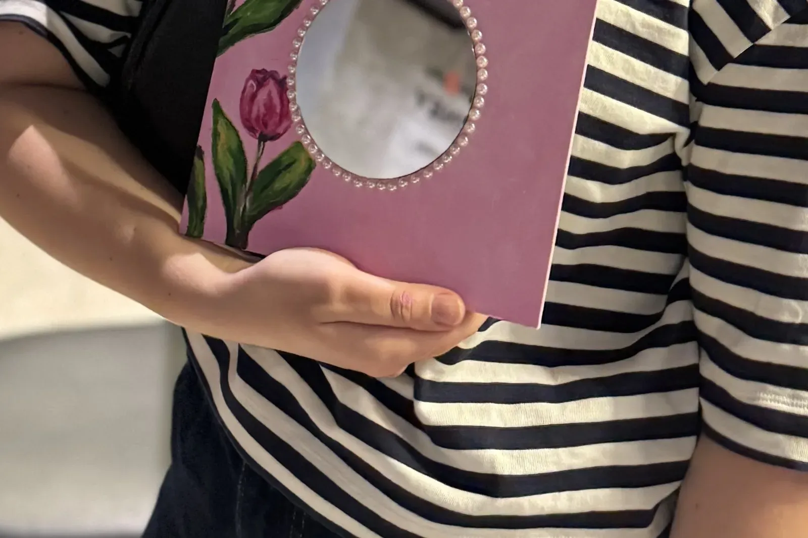 A guest holding her finished pink tulip mirror with pearls around the glass
